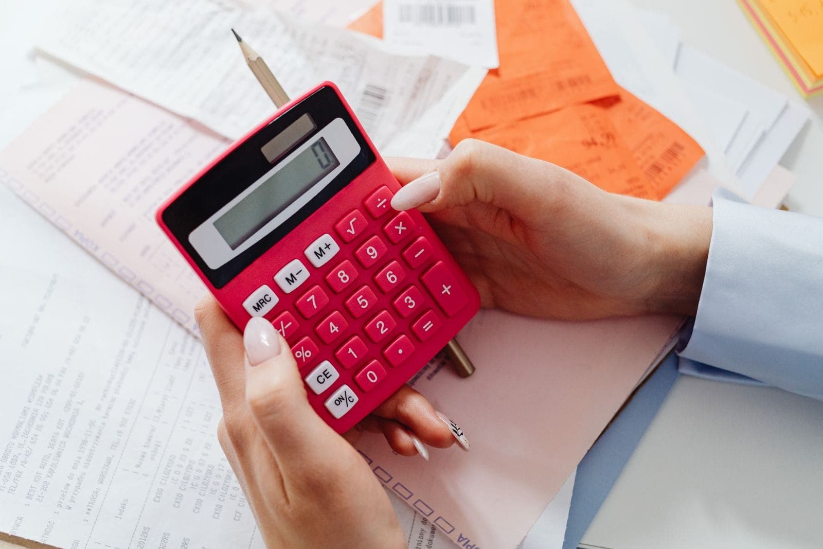 Hands holding a calculator over invoices